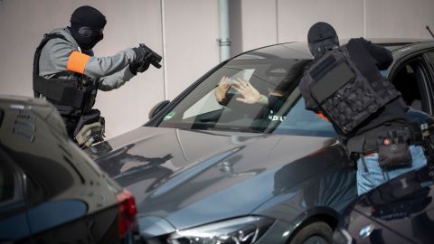 Zwei Beamte des mobilen Einsatzkommandos stoppen in einer Übung ein Auto. Sie zielen mit Pistolen auf den Fahrer. Dieser hält die Hände abwehrend nach vorne.